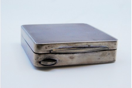 Caixa de comprimidos em prata com tampa em prata escovada e saliência para abrir.